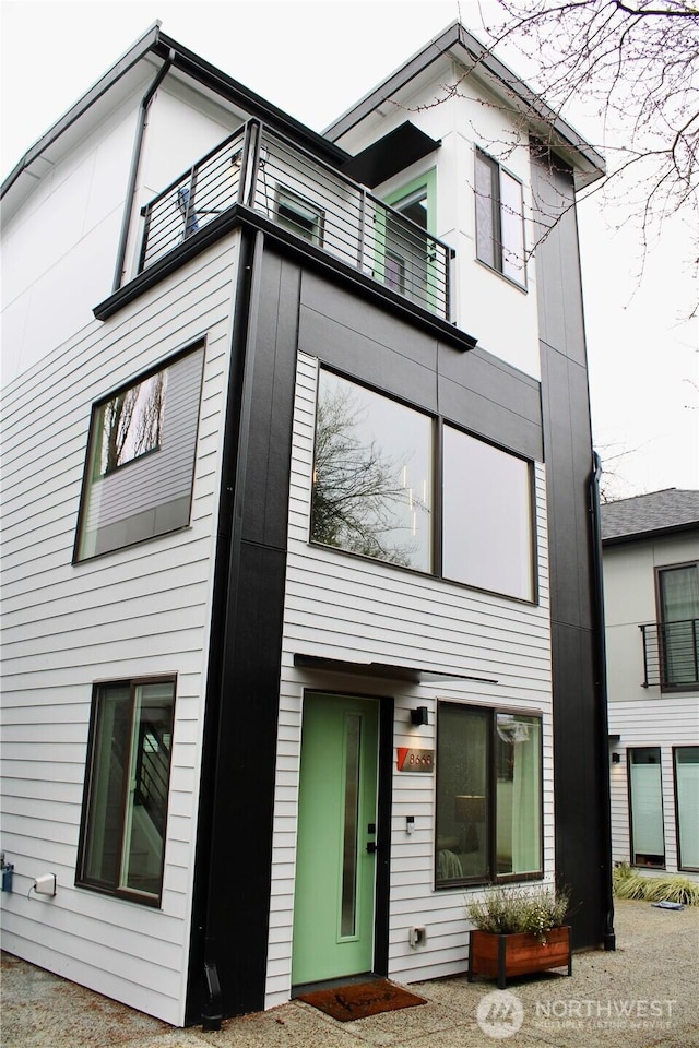 view of front of house featuring elevator and a balcony