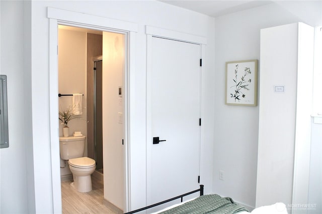 bedroom with connected bathroom and light wood-type flooring