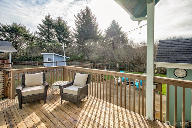 wooden deck featuring a storage unit, an outdoor hangout area, an outdoor structure, and fence