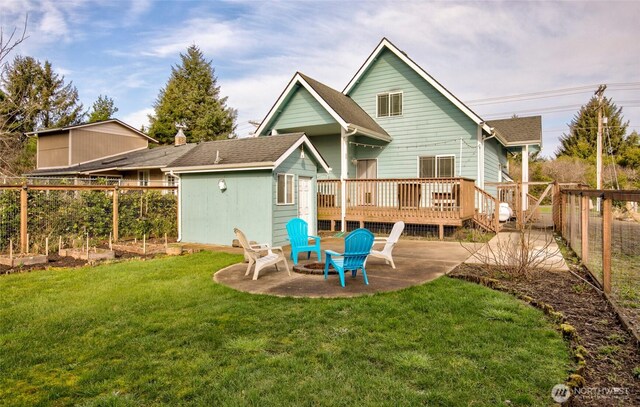 rear view of house with an outbuilding, a vegetable garden, a fenced backyard, a deck, and a lawn