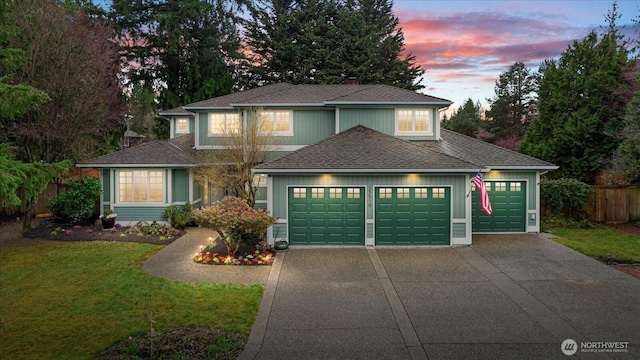 traditional home featuring a front yard, fence, driveway, an attached garage, and a shingled roof