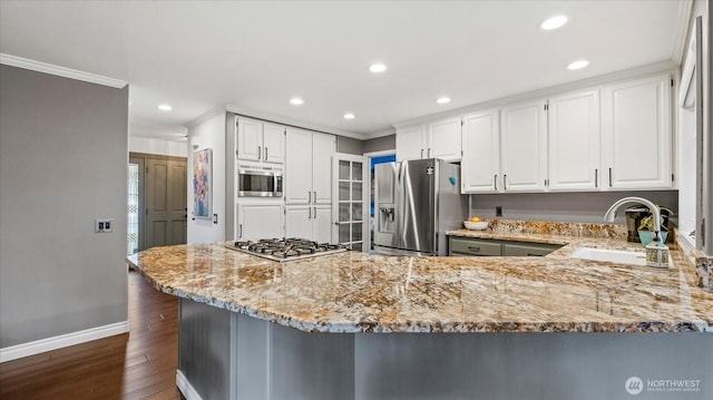 kitchen with ornamental molding, light stone counters, appliances with stainless steel finishes, and a sink