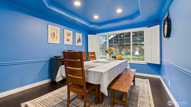 dining area featuring baseboards, crown molding, a tray ceiling, and wood finished floors