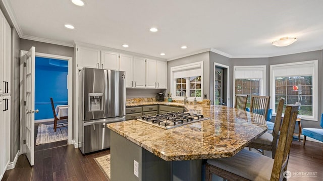 kitchen featuring light stone counters, dark wood-style floors, appliances with stainless steel finishes, a peninsula, and crown molding