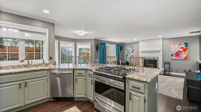 kitchen featuring visible vents, a sink, appliances with stainless steel finishes, a peninsula, and dark wood-style flooring