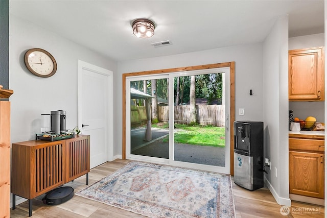 doorway to outside with light wood-style floors, visible vents, and baseboards