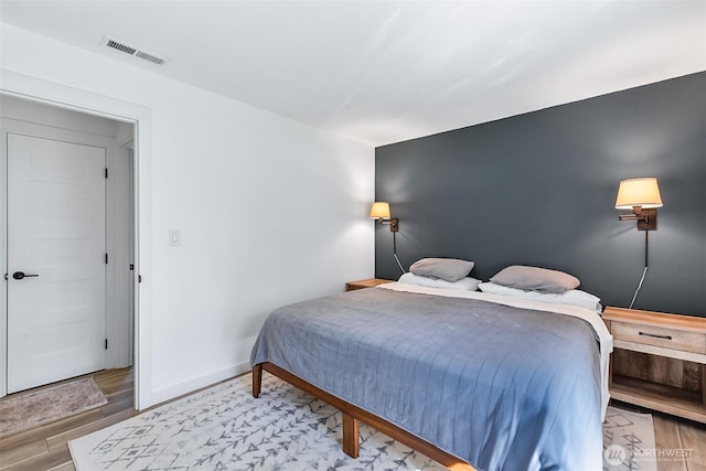 bedroom with visible vents, baseboards, and wood finished floors