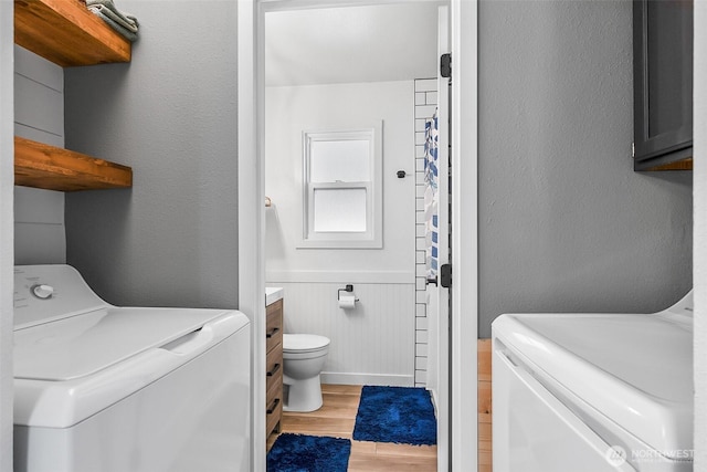 bathroom featuring toilet, independent washer and dryer, wood finished floors, wainscoting, and vanity