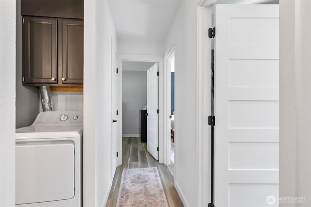 laundry area featuring wood finished floors, cabinet space, baseboards, and washer and clothes dryer