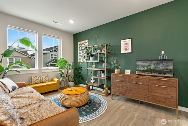 living area featuring light wood-style flooring, baseboards, and visible vents