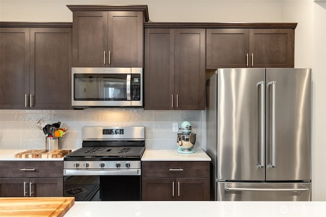 kitchen featuring dark brown cabinetry, stainless steel appliances, light countertops, and tasteful backsplash