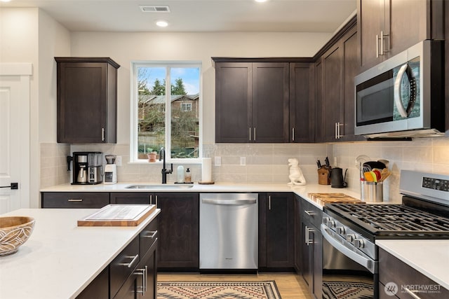 kitchen featuring a sink, visible vents, appliances with stainless steel finishes, and dark brown cabinets