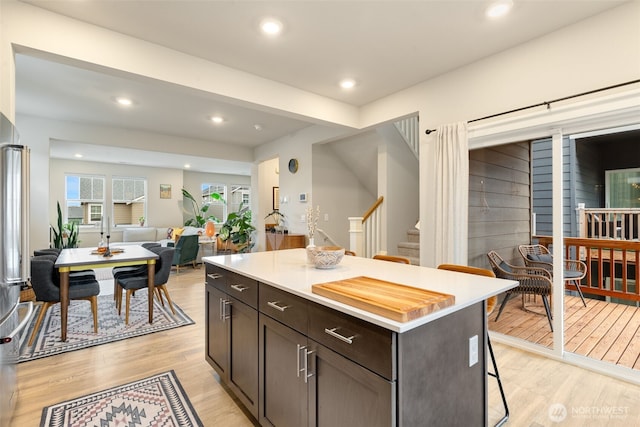 kitchen with a breakfast bar, light wood-style flooring, a center island, recessed lighting, and dark brown cabinetry