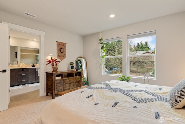 bedroom featuring light carpet, visible vents, recessed lighting, and ensuite bath