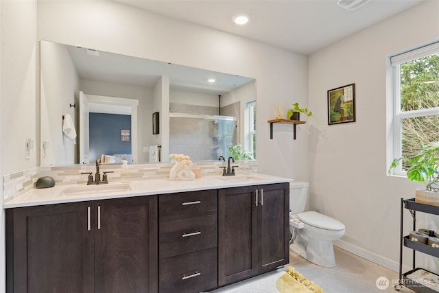 full bathroom featuring decorative backsplash, a stall shower, toilet, and a sink