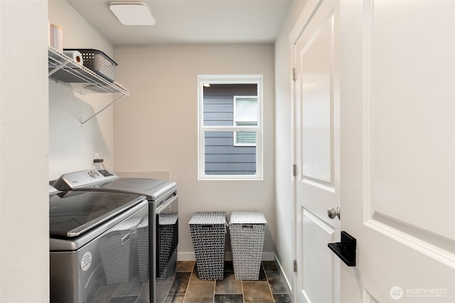 washroom with baseboards, washing machine and dryer, and laundry area