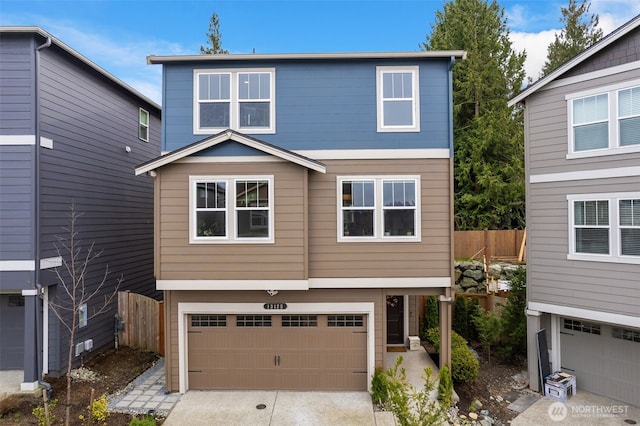 view of front of property featuring an attached garage, fence, and driveway