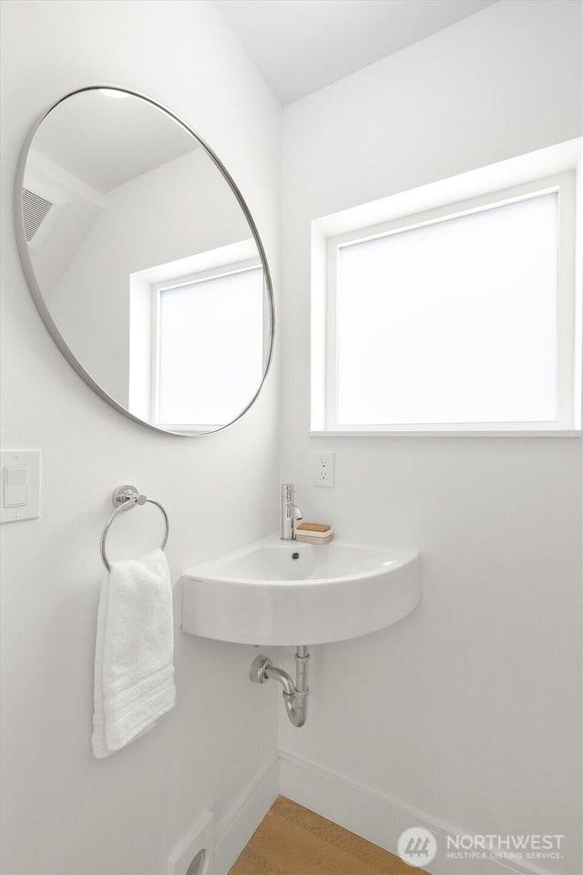 bathroom with a sink, baseboards, and wood finished floors