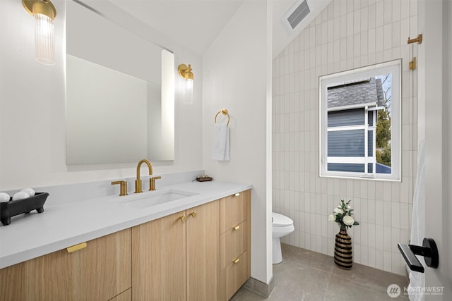 bathroom featuring tile patterned flooring, visible vents, tile walls, toilet, and vanity