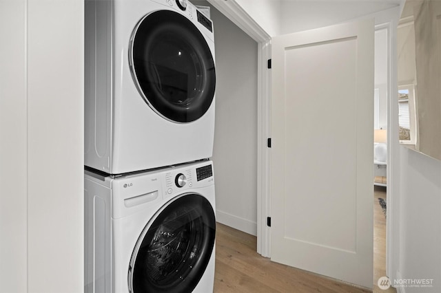 clothes washing area with stacked washer / dryer, laundry area, and wood finished floors