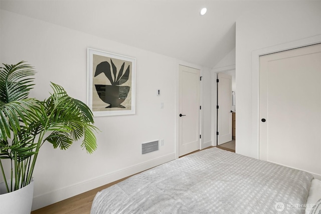 bedroom with visible vents, baseboards, lofted ceiling, recessed lighting, and wood finished floors