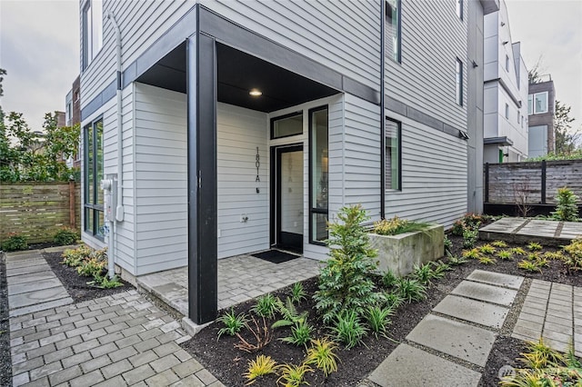 view of exterior entry featuring a patio and fence