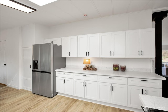 kitchen with white cabinetry, light wood-style flooring, and stainless steel fridge