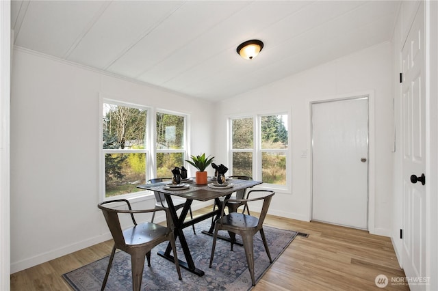 dining area featuring baseboards, light wood-style floors, and lofted ceiling