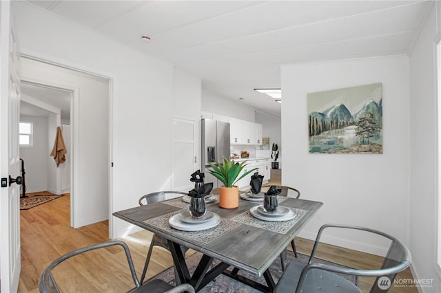 dining space featuring baseboards and light wood finished floors