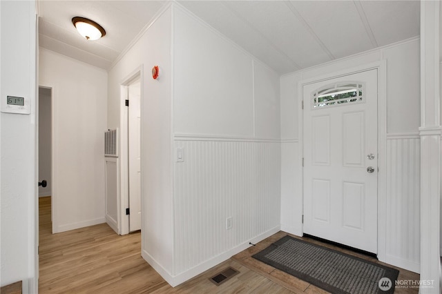 foyer featuring lofted ceiling, crown molding, visible vents, and light wood finished floors