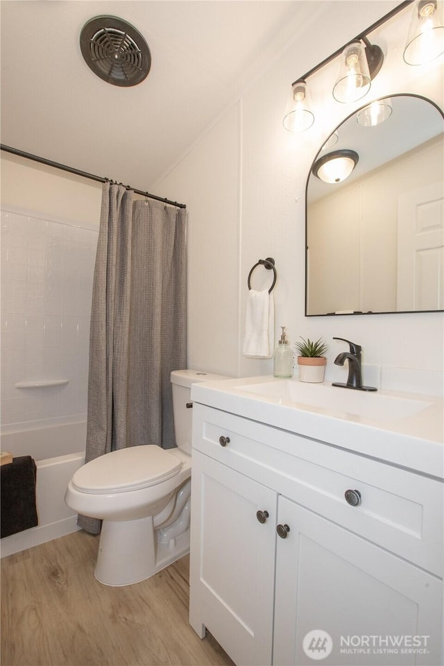 bathroom with visible vents, toilet, wood finished floors, vanity, and shower / bathtub combination with curtain