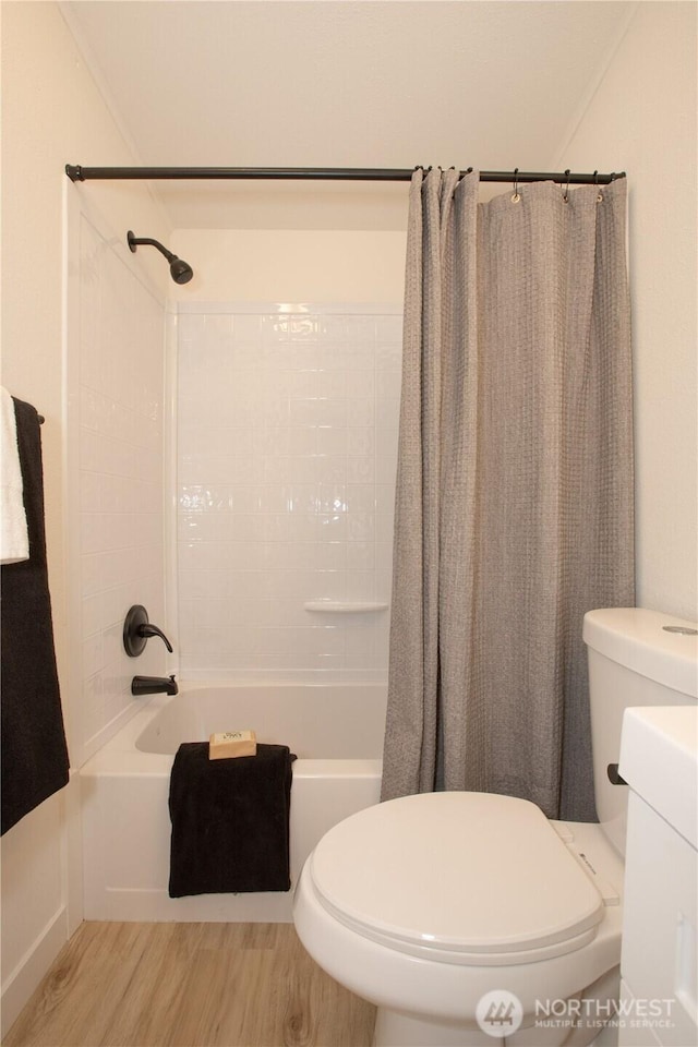 bathroom featuring toilet, wood finished floors, and shower / bath combo