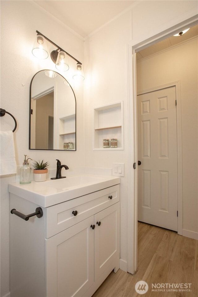 bathroom with ornamental molding, vanity, and wood finished floors