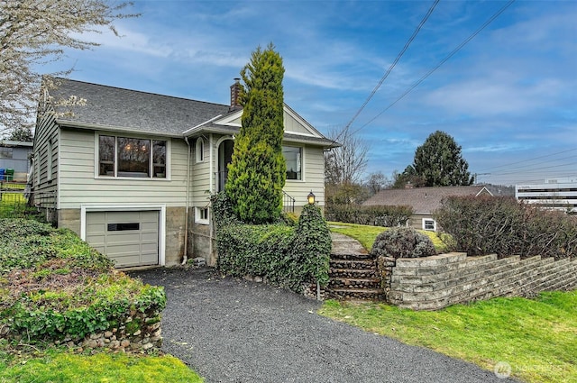 view of front of property featuring aphalt driveway, an attached garage, and a chimney