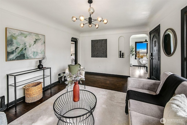 living area with arched walkways, a chandelier, baseboards, and wood finished floors