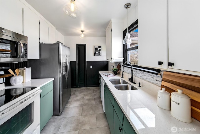 kitchen with a sink, white appliances, white cabinets, wainscoting, and green cabinetry