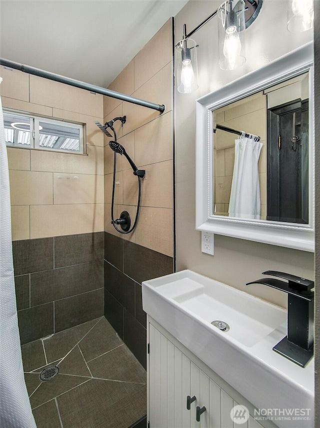 bathroom with tiled shower and vanity