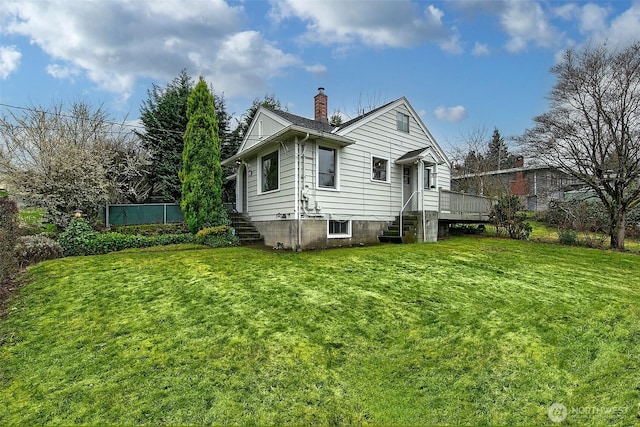 rear view of property featuring a chimney and a yard