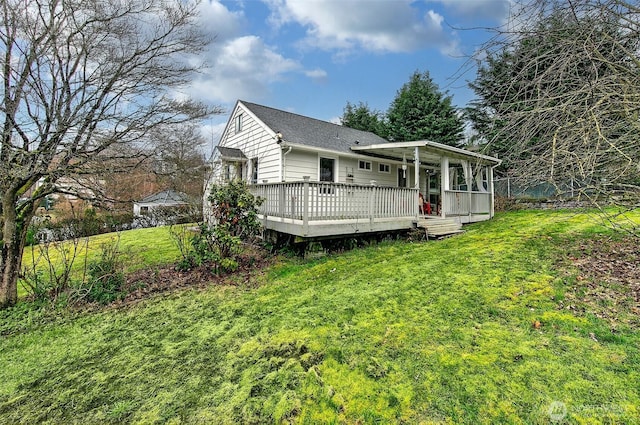 rear view of property featuring a wooden deck, a lawn, and a shingled roof