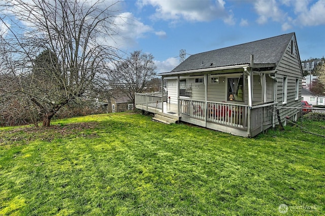 rear view of property with a yard, roof with shingles, and a wooden deck