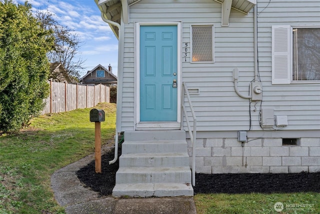 property entrance featuring fence and a lawn