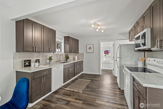 kitchen with dark wood-type flooring, a sink, white appliances, decorative backsplash, and dark brown cabinets