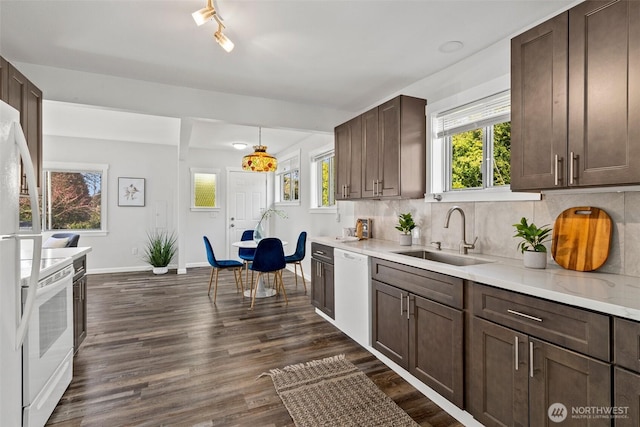 kitchen with backsplash, dark wood finished floors, light countertops, white appliances, and a sink