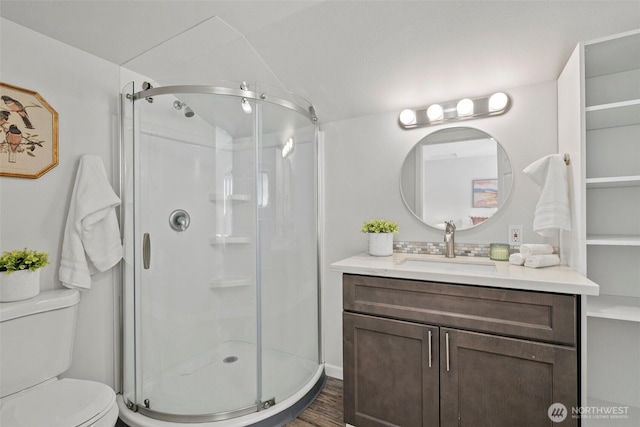 full bath featuring a stall shower, toilet, vanity, and wood finished floors