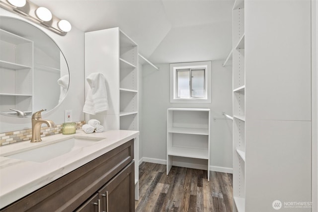 bathroom featuring a spacious closet, vaulted ceiling, vanity, and wood finished floors