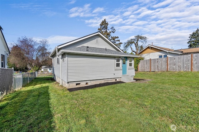 rear view of house with a lawn and a fenced backyard