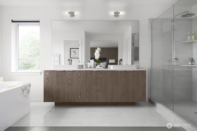 bathroom with tile patterned floors, a freestanding tub, a sink, a shower stall, and double vanity