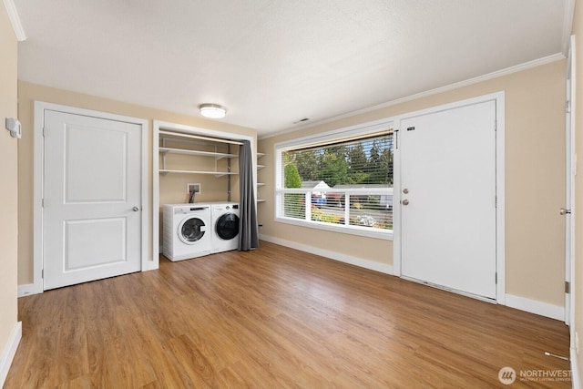 washroom with laundry area, light wood-style flooring, baseboards, and washing machine and clothes dryer