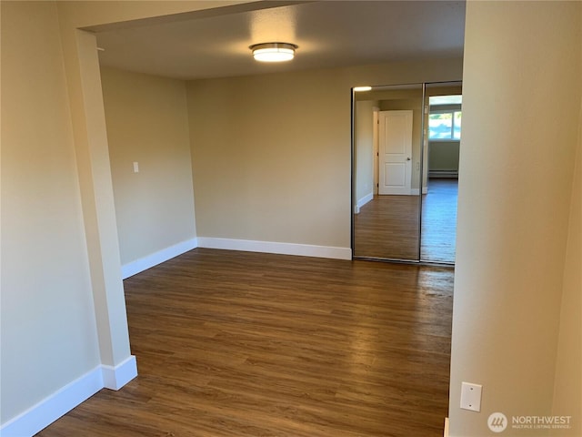 unfurnished room with dark wood-style floors and baseboards