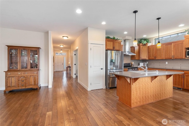 kitchen with wood-type flooring, brown cabinets, appliances with stainless steel finishes, and a sink